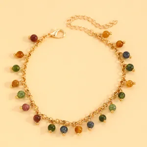 Detailed view of a vintage gold chain bracelet with vibrant colorful dangling beads.