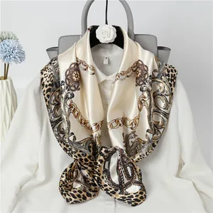 Detailed view of luxury leopard and chain print satin square scarf on white shirt.