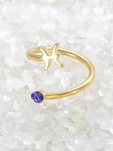 Close-up of gold Pisces zodiac ring with a purple crystal on white stones.