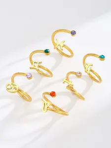 Group of gold titanium steel zodiac rings featuring various colorful gemstones and symbols