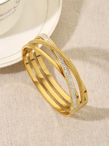 Detailed view of the crossed 18K gold-plated bangle layers with brilliant rhinestone accents