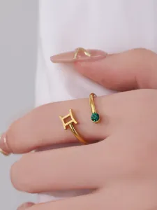 Detailed macro view of gold Gemini zodiac ring with a sparkling green gemstone insert