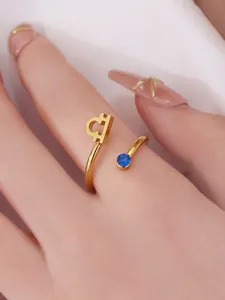 Close-up of golden Libra zodiac titanium steel ring featuring a small blue gemstone inlay