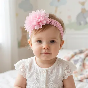 Detail showing a pink chiffon flower headband on a baby girl with white lace dress