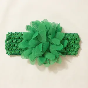 Detailed macro shot of a green baby headband featuring a large layered chiffon flower