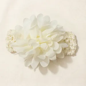 Detail view of large white chiffon flower on soft knitted elastic headband for babies