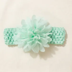 Detailed macro view of a soft mint green chiffon flower on an elastic baby headband