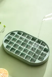 Detailed action shot of water pouring into a 36-grid green silicone ice cube tray