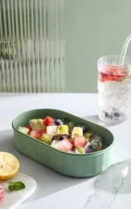 Close-up of green silicone ice cube mold filled with colorful fruit ice cubes on marble table