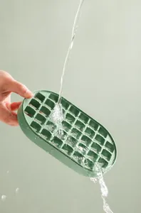 Macro view of water rinsing a green silicone ice cube tray to demonstrate easy cleaning process