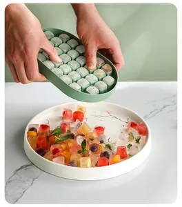 Close-up of a flexible green silicone ice cube tray releasing colorful fruit ice cubes