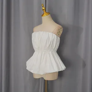 Detailed side view of a white strapless tube top with gathered waist on a beige mannequin