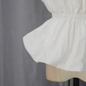 Detailed macro view showing the elastic waist and flared peplum hem of a white tube top garment