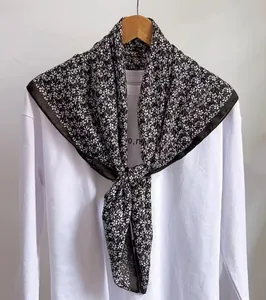 Detail eines eleganten schwarz-weißen quadratischen Schals mit feinem Blümchenmuster