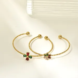 Close-up of gold-plated titanium steel cuff bangles with colorful zircon flower charms