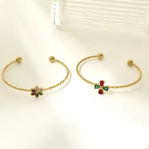 Close-up of elegant gold titanium steel cuff bracelets featuring vibrant zircon stone designs.