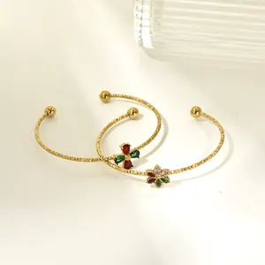 Close-up of gold titanium steel cuffs featuring vibrant colorful zircon flower accents.