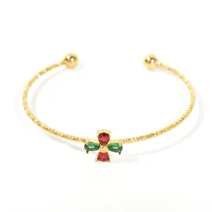 Detailed view of a gold-toned titanium cuff bracelet with red and green zircons.