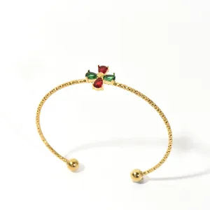 Detailed view of a gold-toned cuff bangle featuring red and green teardrop stones.