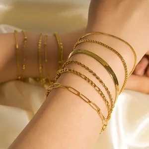 Detailansicht mehrerer geschichteter 18 Karat vergoldeter Edelstahlarmbänder am Handgelenk