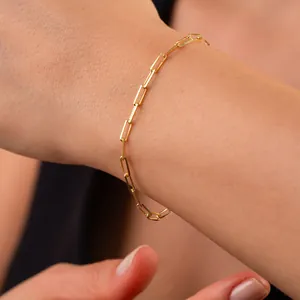 Nahaufnahme eines 18k vergoldeten Edelstahl-Büroklammer-Armbands an einem Handgelenk