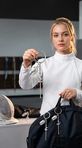Modelo mostrando un llavero de máscara y espada de esgrima unido a una bolsa de deporte.