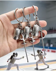Imagen detallada de llaveros de esgrima de metal plateado con máscaras y floretes