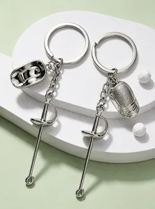 Detalle de llaveros de esgrima plateados con colgantes de sable y máscara en miniatura.