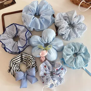 Collection of blue fabric hair scrunchies with stripes, lace, and floral details.