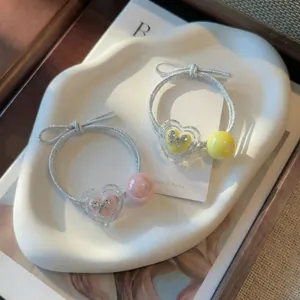 Detail view of heart-shaped hair ties with bow charms and iridescent beads