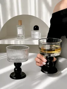 Detailed view of vintage-style ribbed glass goblets with black bases in a sunlit setting