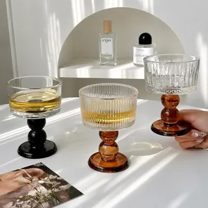 Vintage-style amber and black glass goblets for wine or dessert set on a bright white table.
