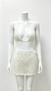 Détail de l'ensemble bikini au crochet blanc et jupe ajourée avec glands pour les vacances.