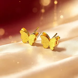 Detailaufnahme von eleganten goldmatten doppellagigen Schmetterlingsohrsteckern auf Seide