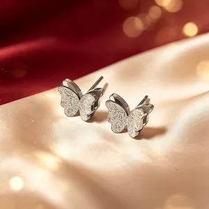 Nahaufnahme eleganter matter doppellagiger Schmetterlingsohrstecker auf goldenem Satin.