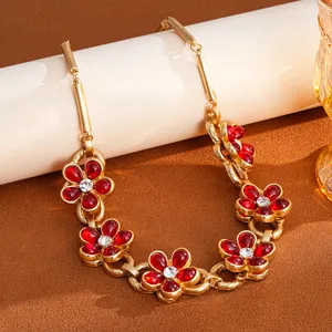Close-up of vintage gold chain bracelet with red rhinestone flowers and white center gems.