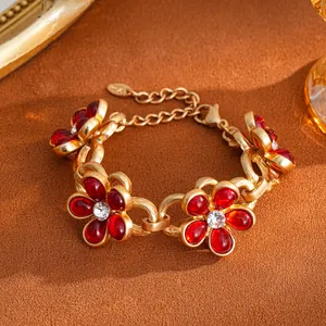 Detailed view of a vintage gold-tone bracelet with red resin flowers and crystals.