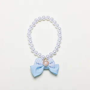 Detailed view of artificial pearl pet collar with blue gingham bow and gold heart pendant