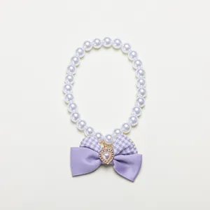 Elegant white faux pearl pet collar featuring a stylish purple bow and heart charm.