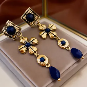 Nahaufnahme von langen Ohrhängern im Retro-Palaststil mit Goldmetall und blauen Steinen