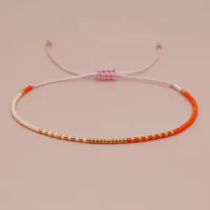 Handmade adjustable seed bead bracelet featuring vibrant orange white and gold accents