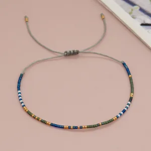 Detailed macro view of an adjustable cord bracelet with blue and gold seed beads.