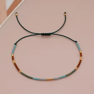 Close-up of handmade adjustable green cord bracelet with colorful rice beads and gold accents