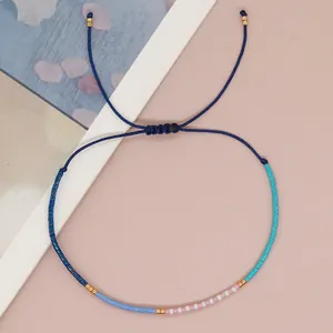 Detail of handmade beaded bracelet with adjustable blue cord and gold beads