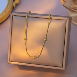 Elegant gold titanium steel bead necklace displayed on a premium textured jewelry box