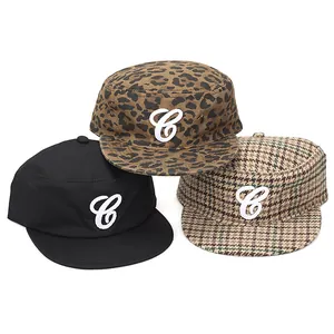 Dettaglio di cappelli militari con ricamo C in fantasie leopardate e pied de poule.