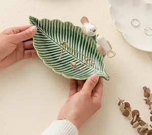 Dettaglio del vassoio per gioielli in ceramica a forma di foglia con decorazioni di uccelli