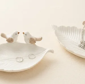 Primo piano di un vassoio portagioie in ceramica a forma di uccello e foglia bianca