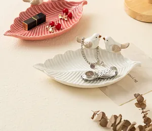 Primo piano di eleganti vassoi per gioielli in ceramica a foglia con accenti di uccelli