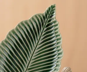 Macro dettaglio della texture smaltata verde del vassoio in ceramica a forma di foglia.